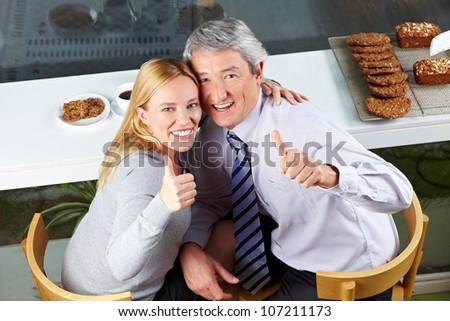 Elderly happy couple holding their thumbs up in cafÃ?Â©