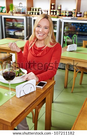 Elderly smiling woman eating her lunch in a restaurant