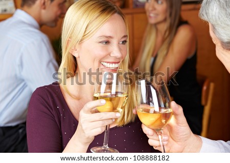Happy elderly woman toasting with glass of white wine to man