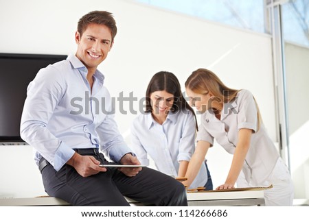 Architect working with tablet computer in his office with his team in the background