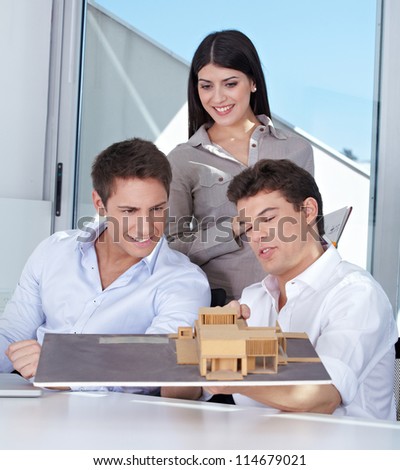 Team of three architects with house model in their office