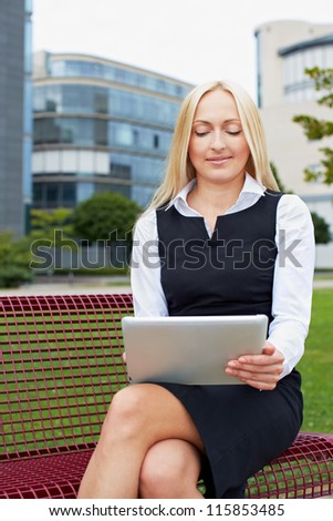 Attractive business woman with tablet computer on a park bench
