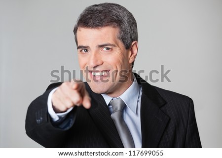 Smiling elderly business man showing I Want You gesture
