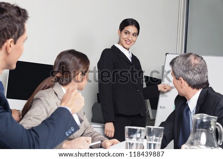 Smiling business woman giving a sales presentation for her team in the office