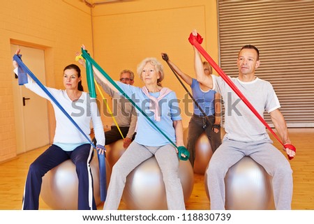 Senior people in gym doing back training with exercise band