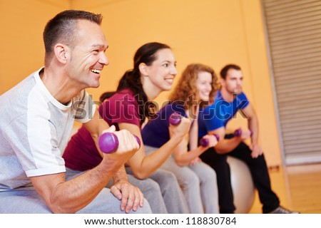 Man smiling in fitness class with dumbbells in a health club