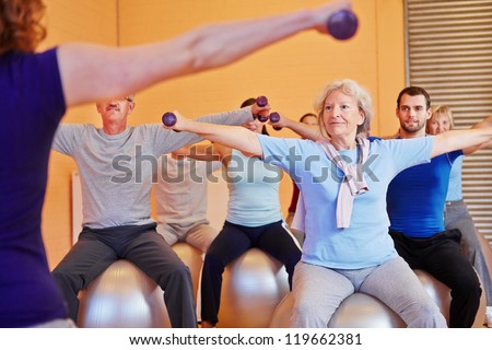 Group doing back training with female fitness instructor in gym