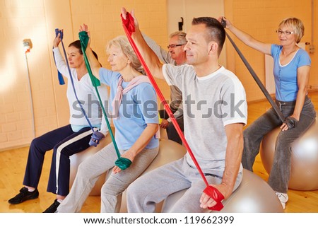 Group doing senior fitness sports with exercise band in gym