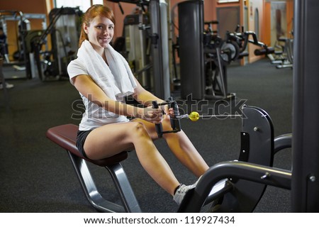 Young woman exercising on cable machine in a fitness center