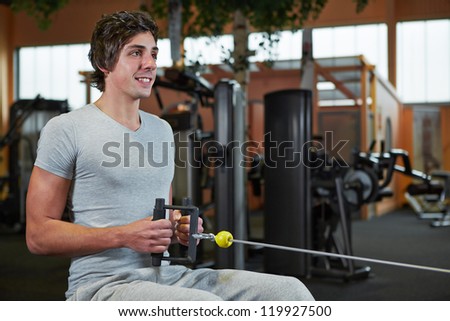 Young man exercising on cable machine in a sport studio
