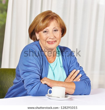 Smiling female senior citizen sitting at coffee table in retirement home