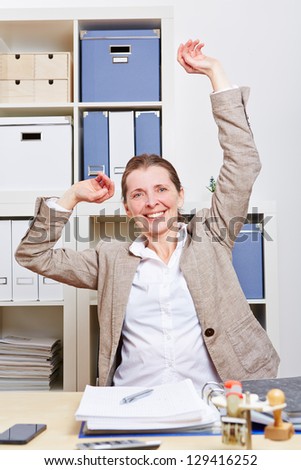 Senior business woman in office stretching her back