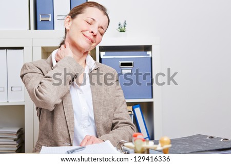 Senior business woman stretching with neck pain in her office