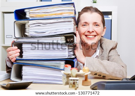 Happy business woman in office with a stack of files