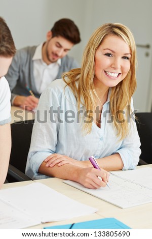 Happy female student in college class studying