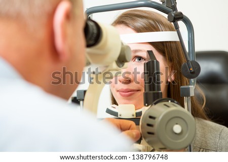 Optometrist checking eye of young woman with a slit lamp