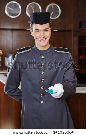 Happy friendly concierge giving hotel key card