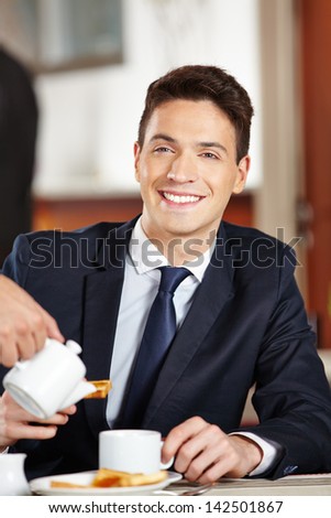 Happy businessman eating breakfast in coffee shop of a hotel