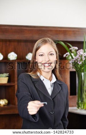 Smilinge female receptionist at hotel offering a key card