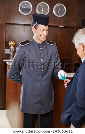 Helpful concierge giving senior man his hotel key card