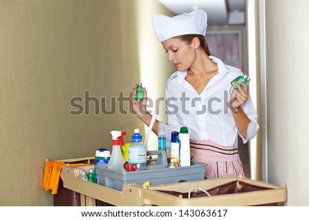 Hotel maid working with cleaning cart and cleaning supplies
