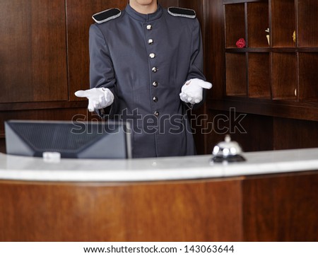 Concierge with empty white gloves behind hotel reception counter
