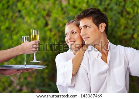 Waiter giving couple glasses of champagne to the pool