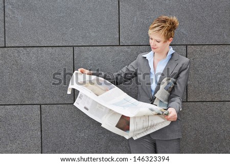 Business woman on the move holding a newspaper in windy weather