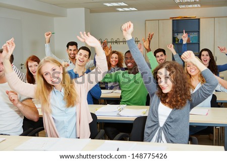 Many cheering students with hands raised in university class