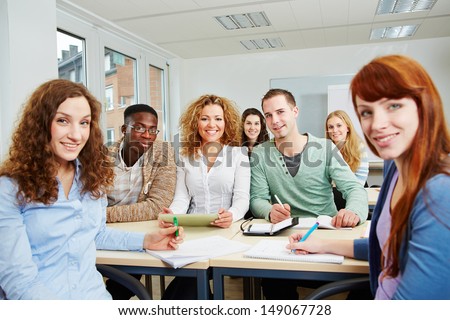 Many smiling students in university class working as a team