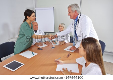 Doctor giving handshake to new team member in a welcome meeting