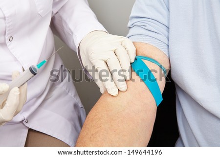 Doctor with syringe at blood withdrawal looking for a blood vessel