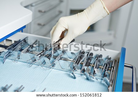 Hand of dentist reaching for different dental tools in a cabinet
