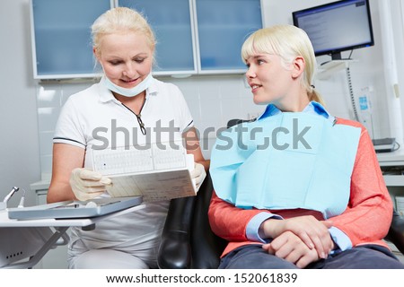 Dentist reading medical record of patient prior to dental treatment