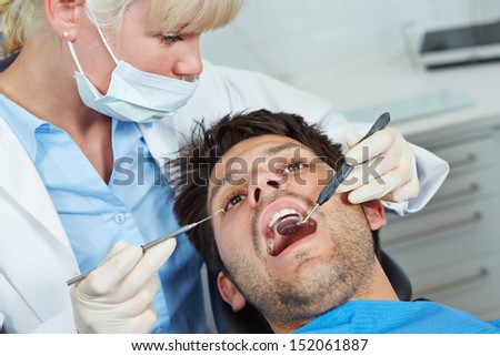 Dentist examining mouth of patient with mirror and probe