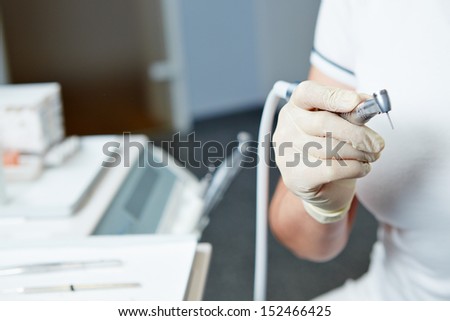 Hand of dentist holding dental drill machine with turbine