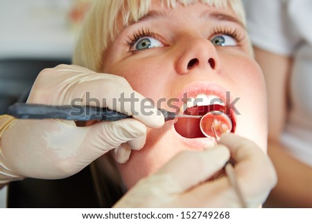 Hands of dentist with probe and mirror in mouth of patient
