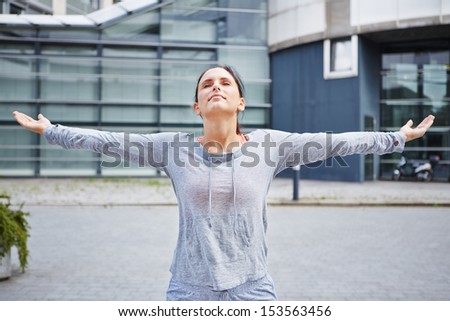 Young athletic woman doing a breathing exercise in the city