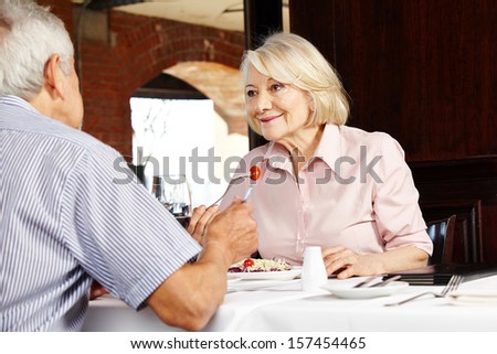 Elderly couple in restaurant talking to each other while eating