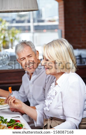 Two happy senior citizens eating together in a nursing home