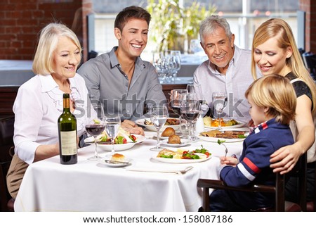 Happy family eating together in a restaurant with child and grandparents