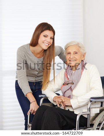Young woman and happy senior citizen in a wheelchair