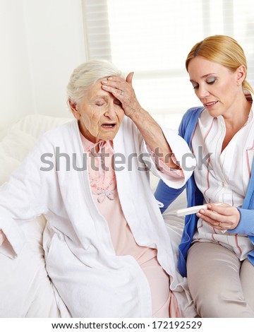 Woman measuring temperature at senior citizen with fever
