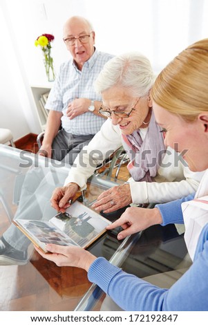 Happy senior woman looking at photos in photo album of her family