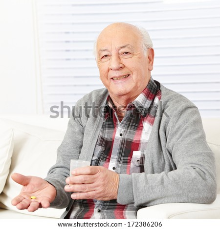 Senior citizen at home taking medical pill with cup of water