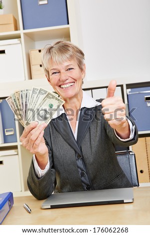 Happy winning business woman holding dollar bills and thumbs up