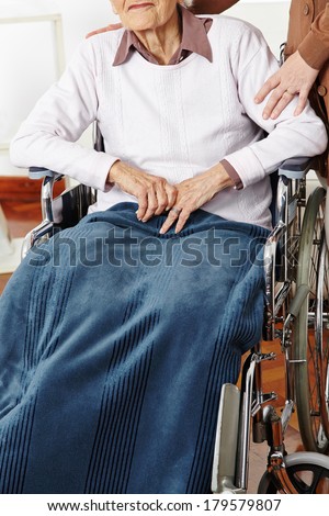 Senior woman in wheelchair getting help from caregiver