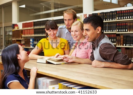 Group of students looking in book at library