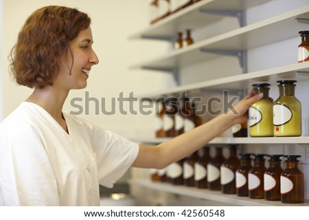 Pharmacist putting drug bottle in shelf in lab