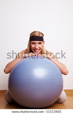 Young woman in sportswear leaning on gym ball